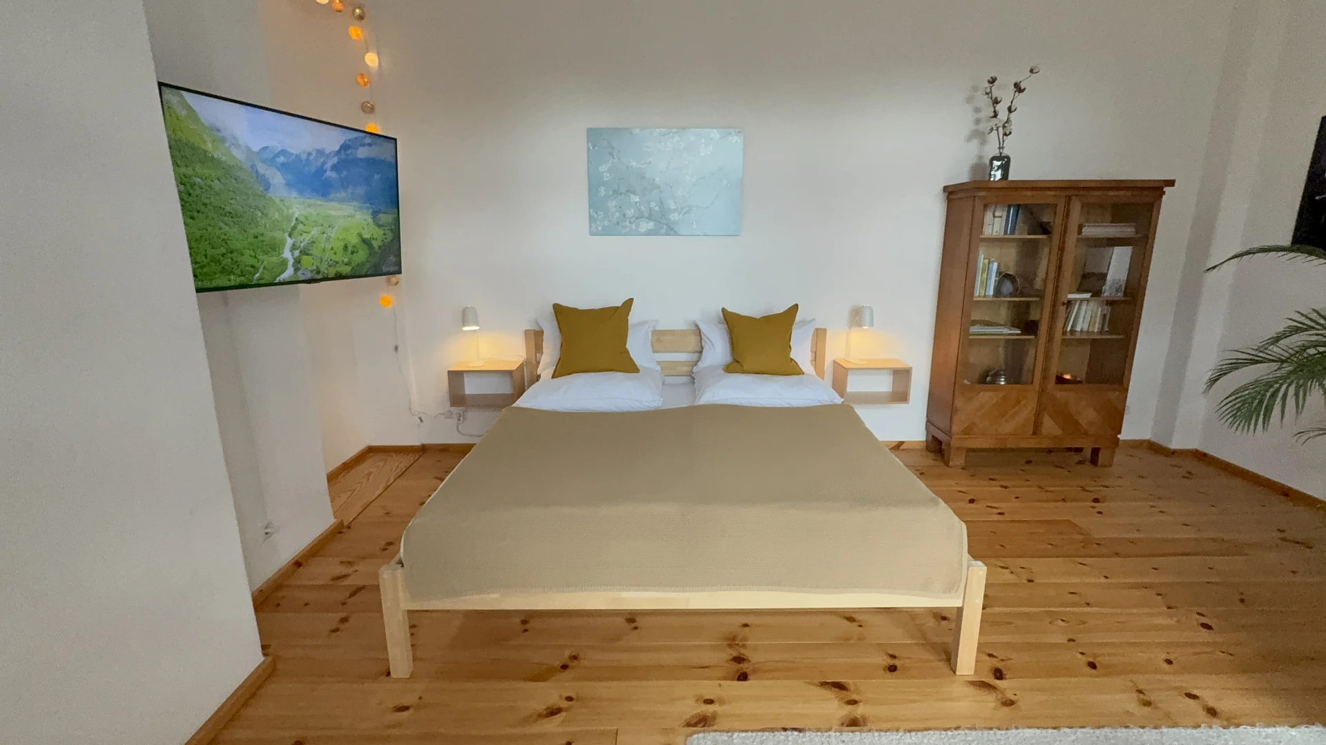 Schlafbereich mit Queensize-Bett, Fernseher und Blick in die Küche