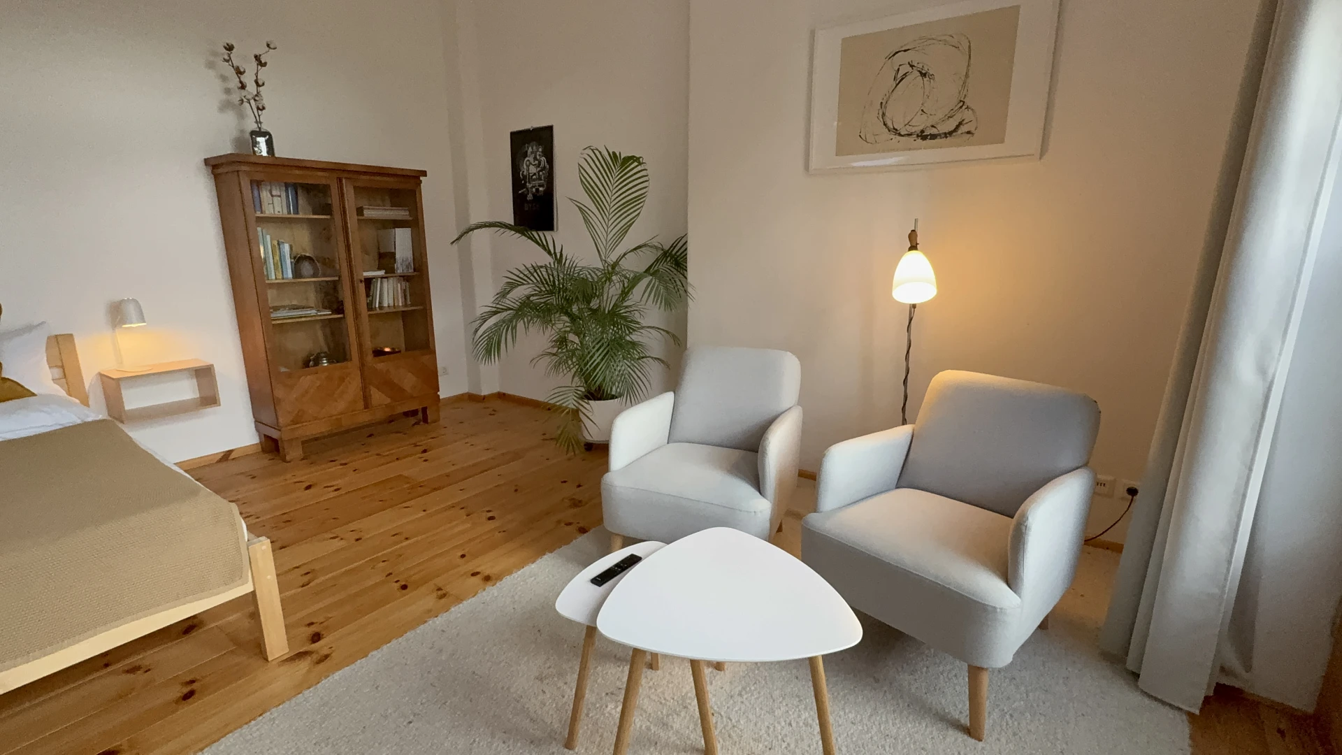 Sitzecke mit zwei Sesseln, Beistelltischen, Stehlampe, Bücherschrank und Palme